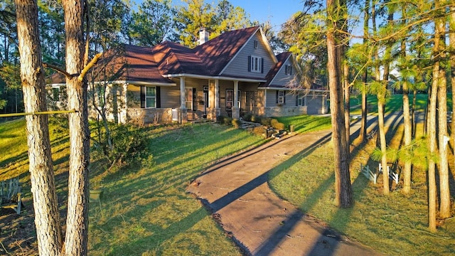 view of front facade featuring driveway, covered porch, a chimney, and a front lawn