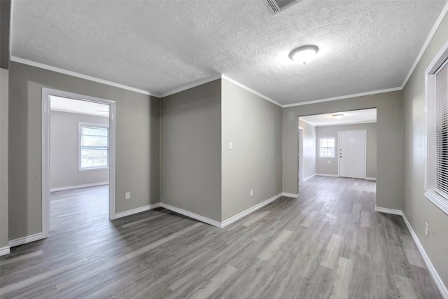 spare room featuring light hardwood / wood-style floors, a textured ceiling, and ornamental molding