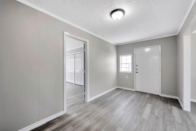 foyer entrance with a textured ceiling, light hardwood / wood-style floors, and crown molding