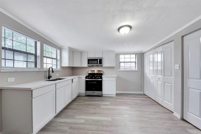 kitchen featuring sink, white cabinetry, stainless steel appliances, and a wealth of natural light