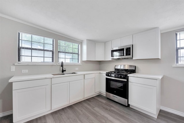 kitchen with white cabinets, sink, stainless steel appliances, and light hardwood / wood-style flooring