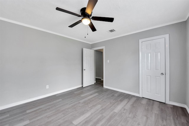 unfurnished bedroom featuring ceiling fan, crown molding, and light wood-type flooring