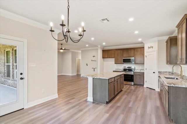 kitchen featuring sink, appliances with stainless steel finishes, a kitchen island, ceiling fan with notable chandelier, and light wood-type flooring