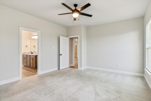 unfurnished bedroom featuring ensuite bathroom, ceiling fan, and light colored carpet