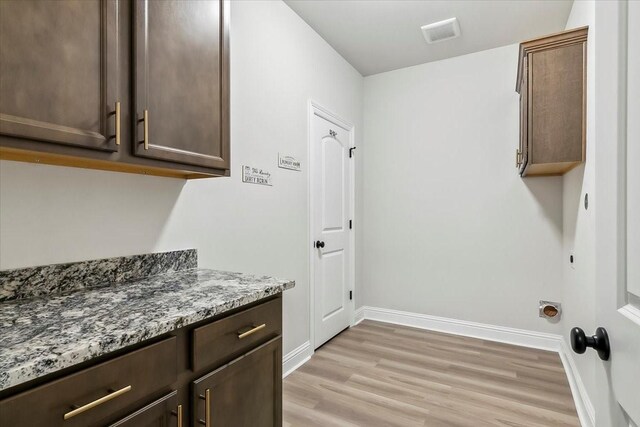 laundry area with light hardwood / wood-style floors and cabinets