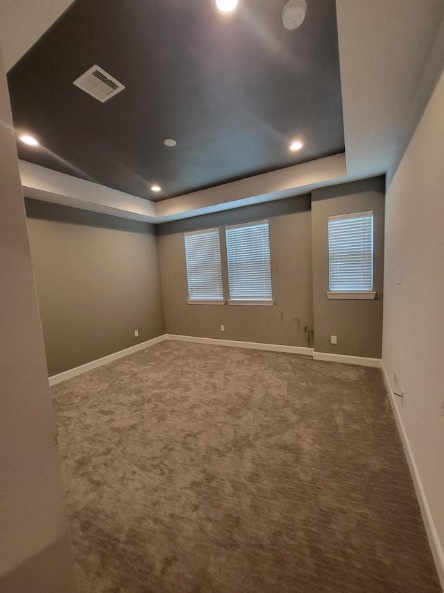 carpeted empty room featuring a tray ceiling