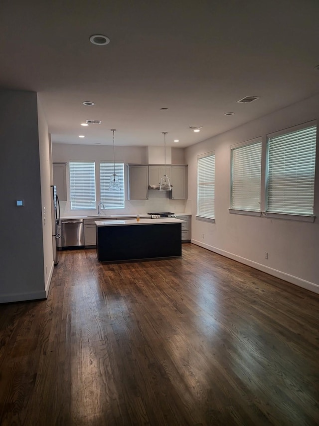 kitchen featuring a center island, dark hardwood / wood-style flooring, decorative light fixtures, gray cabinets, and appliances with stainless steel finishes