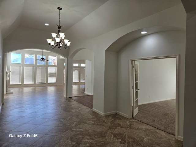 interior space featuring ceiling fan with notable chandelier, french doors, and vaulted ceiling