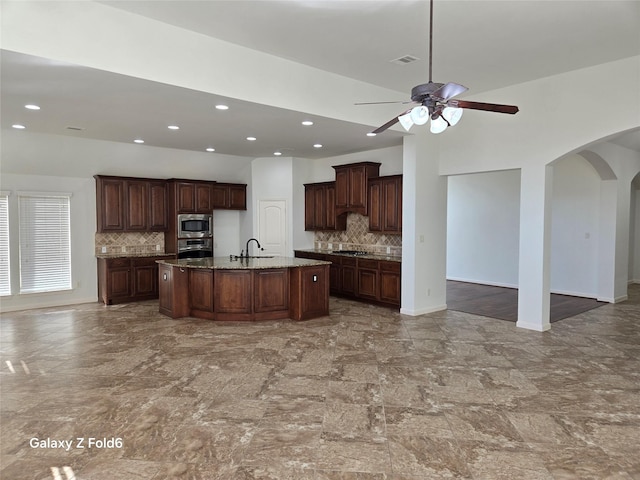 kitchen with tasteful backsplash, sink, an island with sink, and appliances with stainless steel finishes