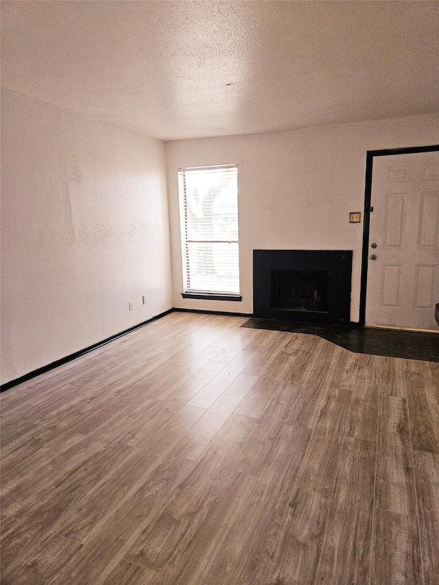 unfurnished living room featuring hardwood / wood-style floors and a textured ceiling