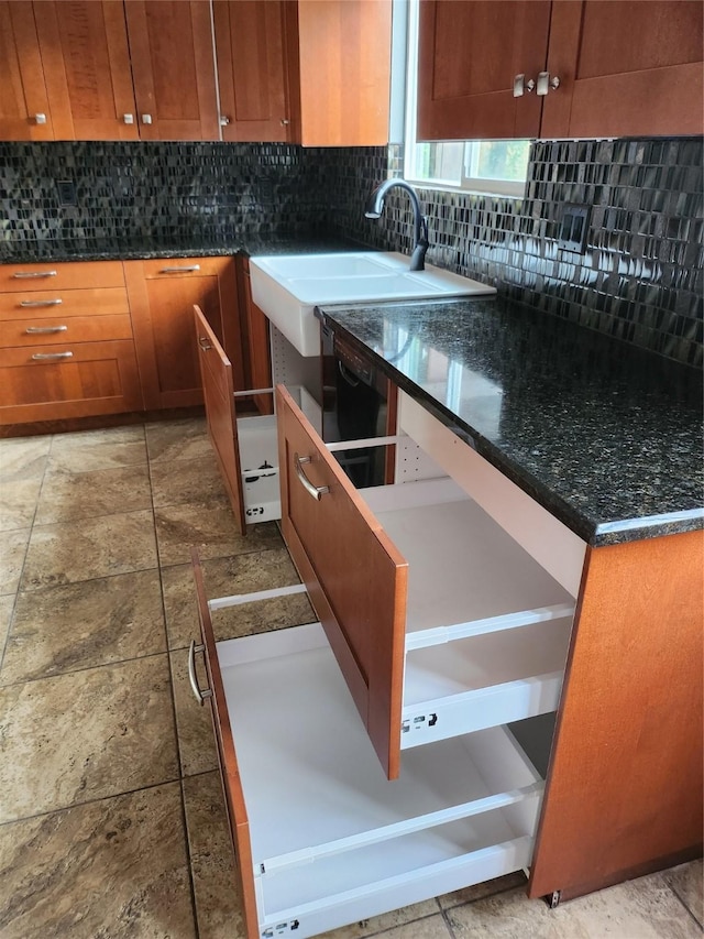 kitchen with backsplash, dark stone countertops, and sink