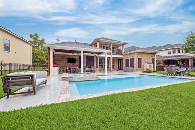 view of swimming pool featuring an in ground hot tub, an outbuilding, ceiling fan, a patio area, and a lawn