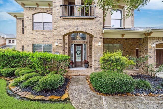 entrance to property with brick siding and a balcony