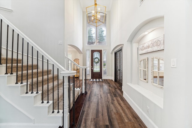 foyer entrance with dark wood-type flooring, a high ceiling, and a chandelier