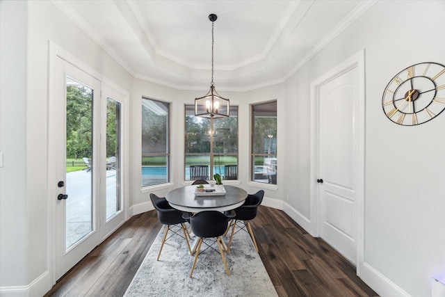 dining space featuring dark hardwood / wood-style flooring, an inviting chandelier, a raised ceiling, and crown molding