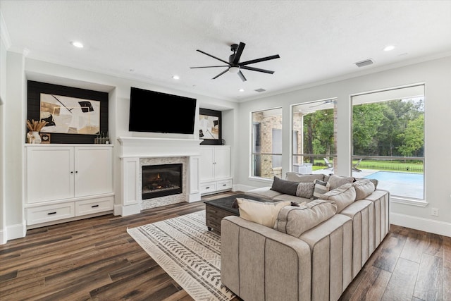 living room with ceiling fan, dark hardwood / wood-style flooring, a textured ceiling, and ornamental molding