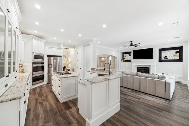 kitchen featuring light stone counters, stainless steel appliances, sink, a center island with sink, and white cabinets