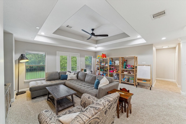 carpeted living room featuring a tray ceiling and ceiling fan