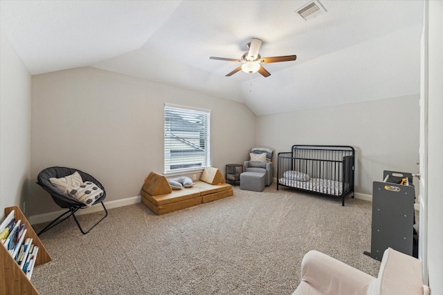 carpeted bedroom with ceiling fan, a crib, and vaulted ceiling