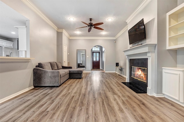 living room with ceiling fan, light hardwood / wood-style floors, crown molding, and a fireplace