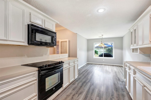 kitchen with black appliances, white cabinets, hanging light fixtures, and hardwood / wood-style floors