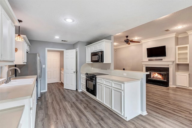 kitchen featuring black appliances, white cabinets, a textured ceiling, decorative light fixtures, and light hardwood / wood-style floors