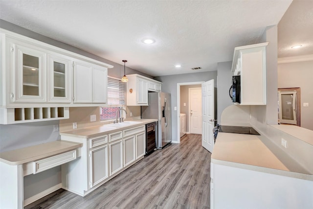 kitchen featuring sink, black appliances, white cabinets, light hardwood / wood-style floors, and hanging light fixtures