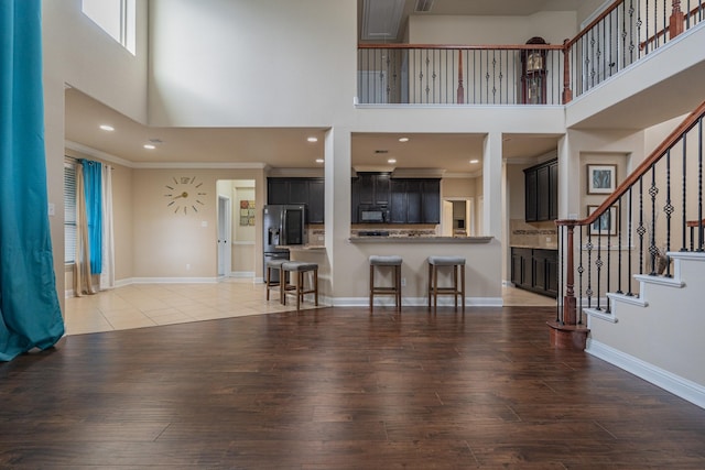 unfurnished living room with ornamental molding, a high ceiling, and hardwood / wood-style flooring