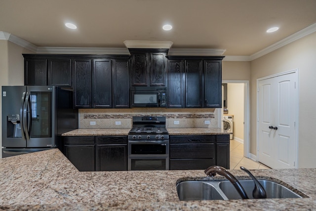 kitchen featuring sink, light stone countertops, tasteful backsplash, stainless steel appliances, and washer / clothes dryer