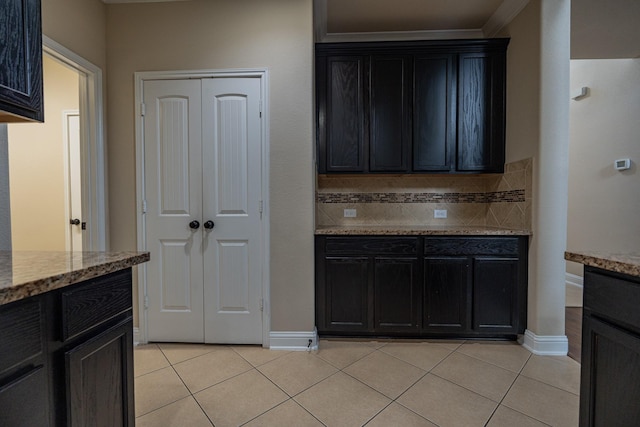 kitchen with decorative backsplash, light tile patterned floors, and light stone counters