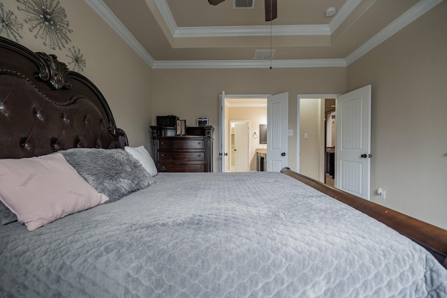 bedroom with ensuite bathroom, a tray ceiling, and ornamental molding