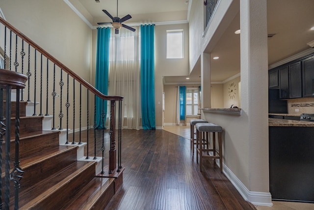 foyer entrance with ceiling fan, a healthy amount of sunlight, dark hardwood / wood-style floors, and crown molding