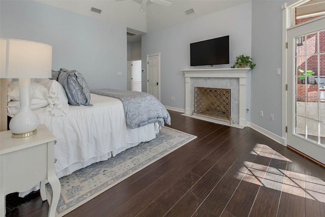 bedroom with a high end fireplace, dark hardwood / wood-style floors, ceiling fan, and access to outside