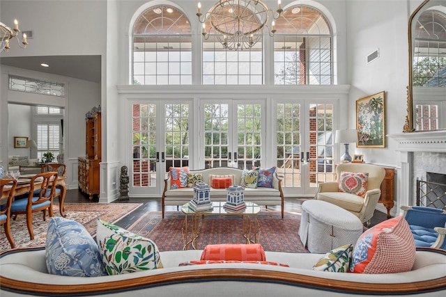 living room with french doors, a towering ceiling, a notable chandelier, and a healthy amount of sunlight