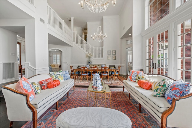 living room featuring a notable chandelier, ornamental molding, a high ceiling, and french doors