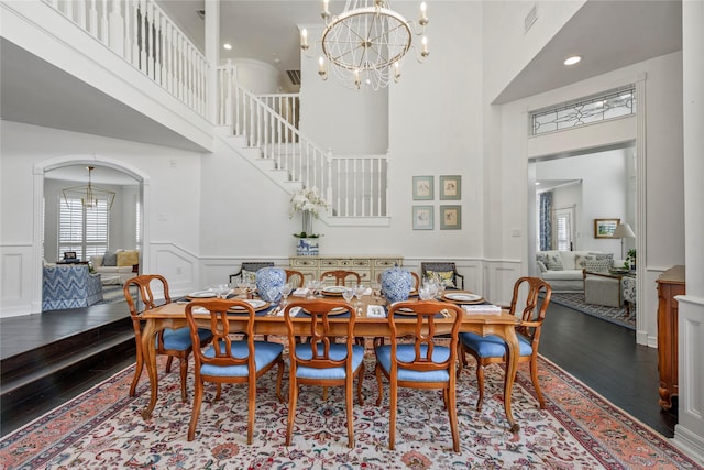 dining room featuring wood-type flooring, an inviting chandelier, and a high ceiling