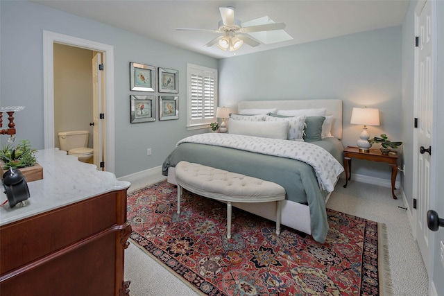 bedroom with ceiling fan, light carpet, connected bathroom, and a skylight