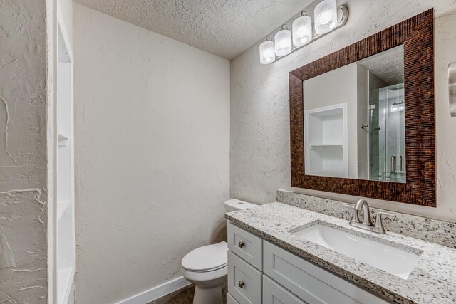 bathroom with vanity, a textured ceiling, and toilet