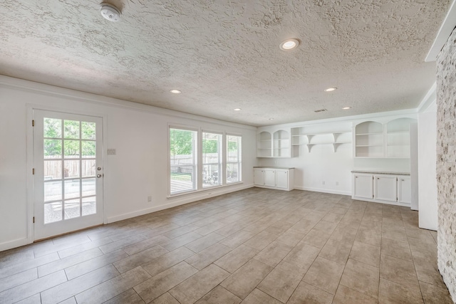 unfurnished living room featuring a healthy amount of sunlight, a textured ceiling, and light wood-type flooring