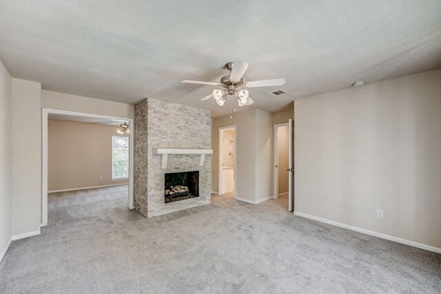 unfurnished living room featuring a textured ceiling, ceiling fan, a fireplace, and light carpet