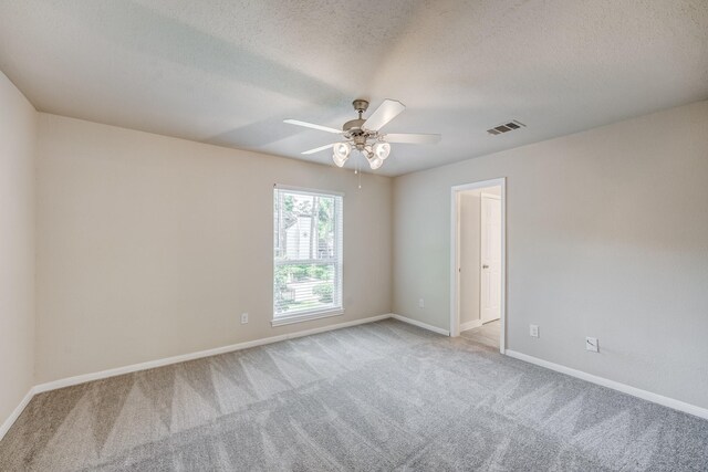 carpeted empty room featuring ceiling fan and a textured ceiling