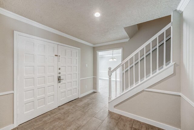 entrance foyer featuring hardwood / wood-style flooring, a chandelier, a textured ceiling, and ornamental molding