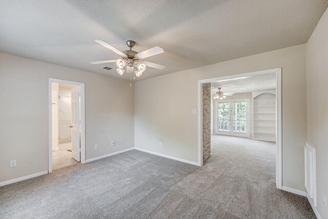 empty room featuring ceiling fan, french doors, light colored carpet, and a textured ceiling