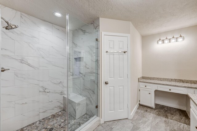 bathroom with vanity, a tile shower, and a textured ceiling