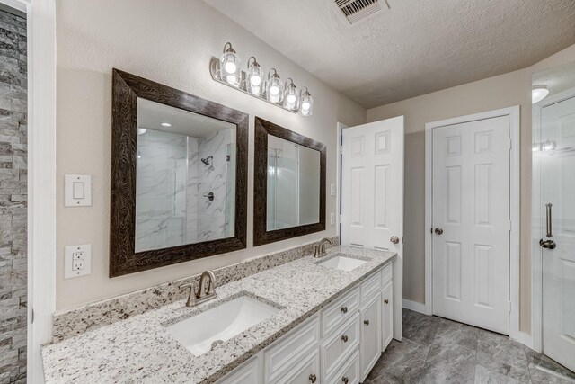 bathroom with vanity, a textured ceiling, and tiled shower