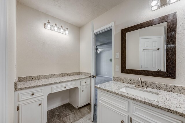 bathroom featuring ceiling fan, vanity, and a textured ceiling