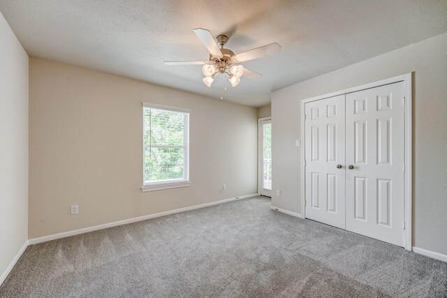 unfurnished bedroom featuring carpet, ceiling fan, a textured ceiling, and a closet