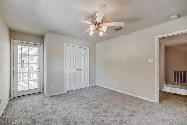 unfurnished bedroom featuring light carpet, a closet, and ceiling fan