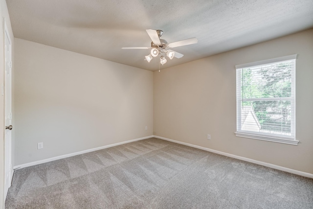 empty room featuring ceiling fan, light colored carpet, and a textured ceiling