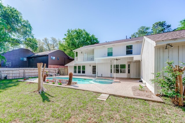 back of house featuring a balcony, ceiling fan, a patio area, a fenced in pool, and a lawn